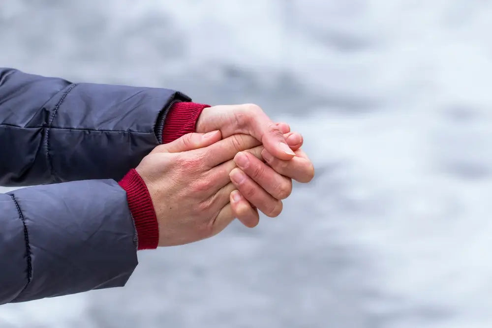 cold red hands being rubbed together with winter coat sleeves showing