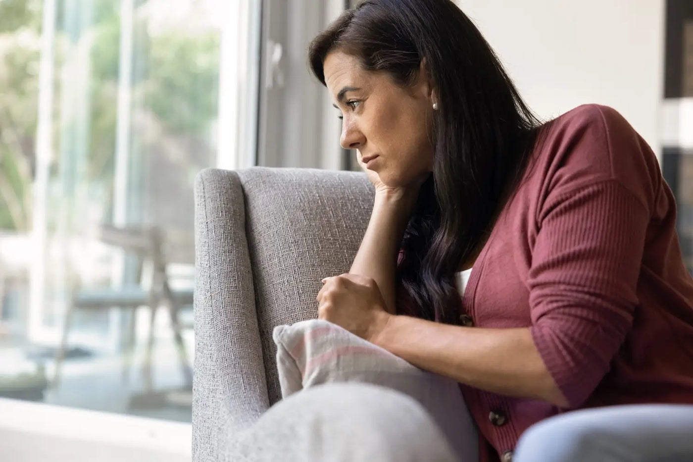 middle age woman on couch gazing out windwo