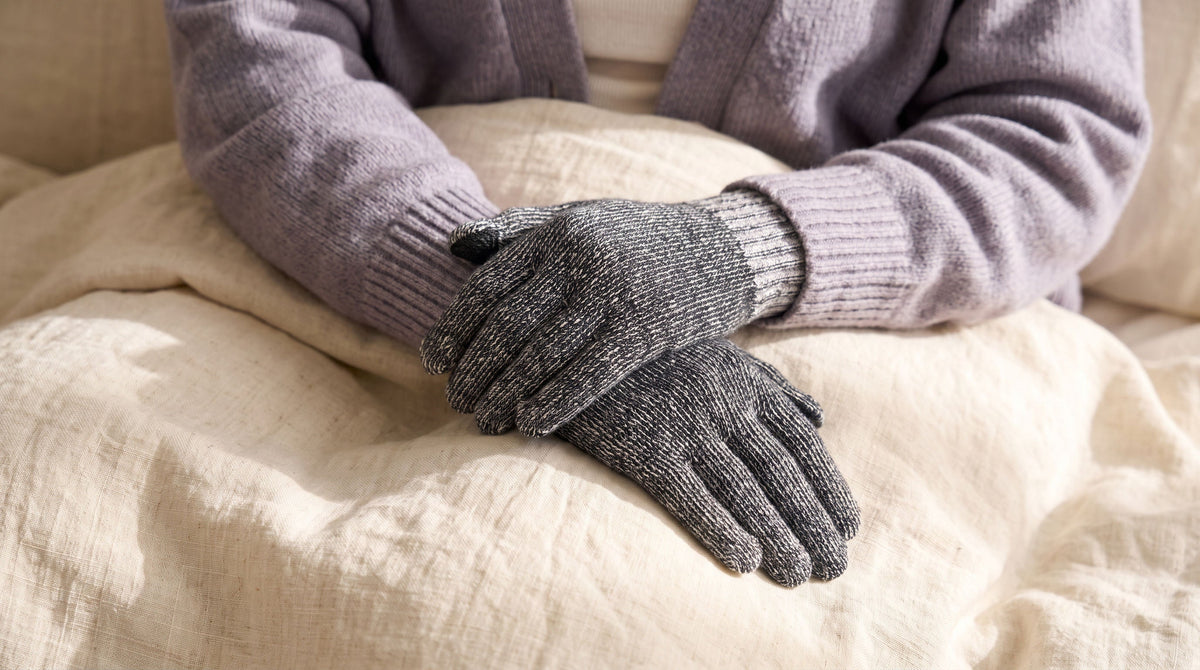 Hands in FibreHeat glove liners resting on a cream linen blanket
