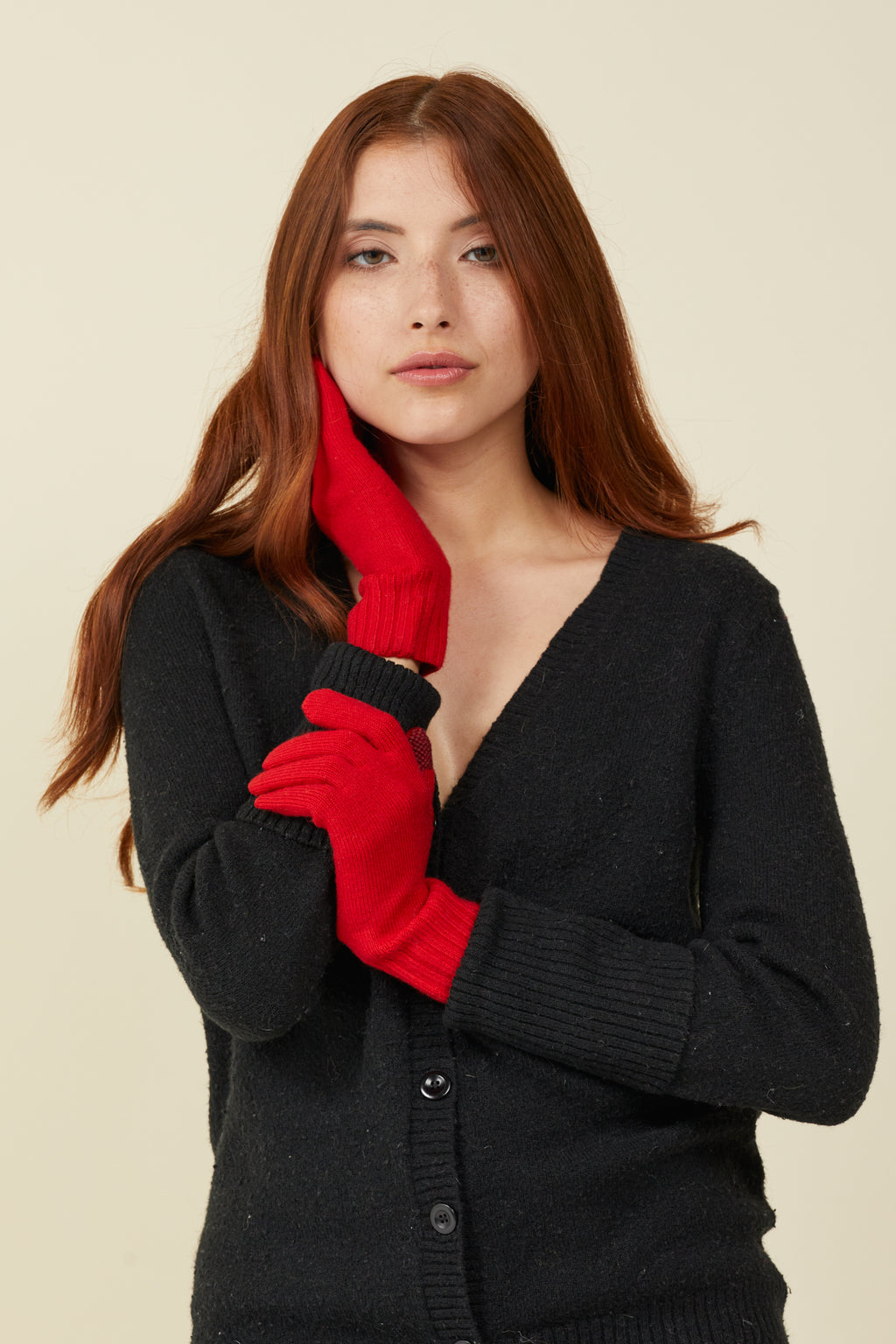 Woman in a black cardigan wearing Vermillion red self-heating merino wool gloves