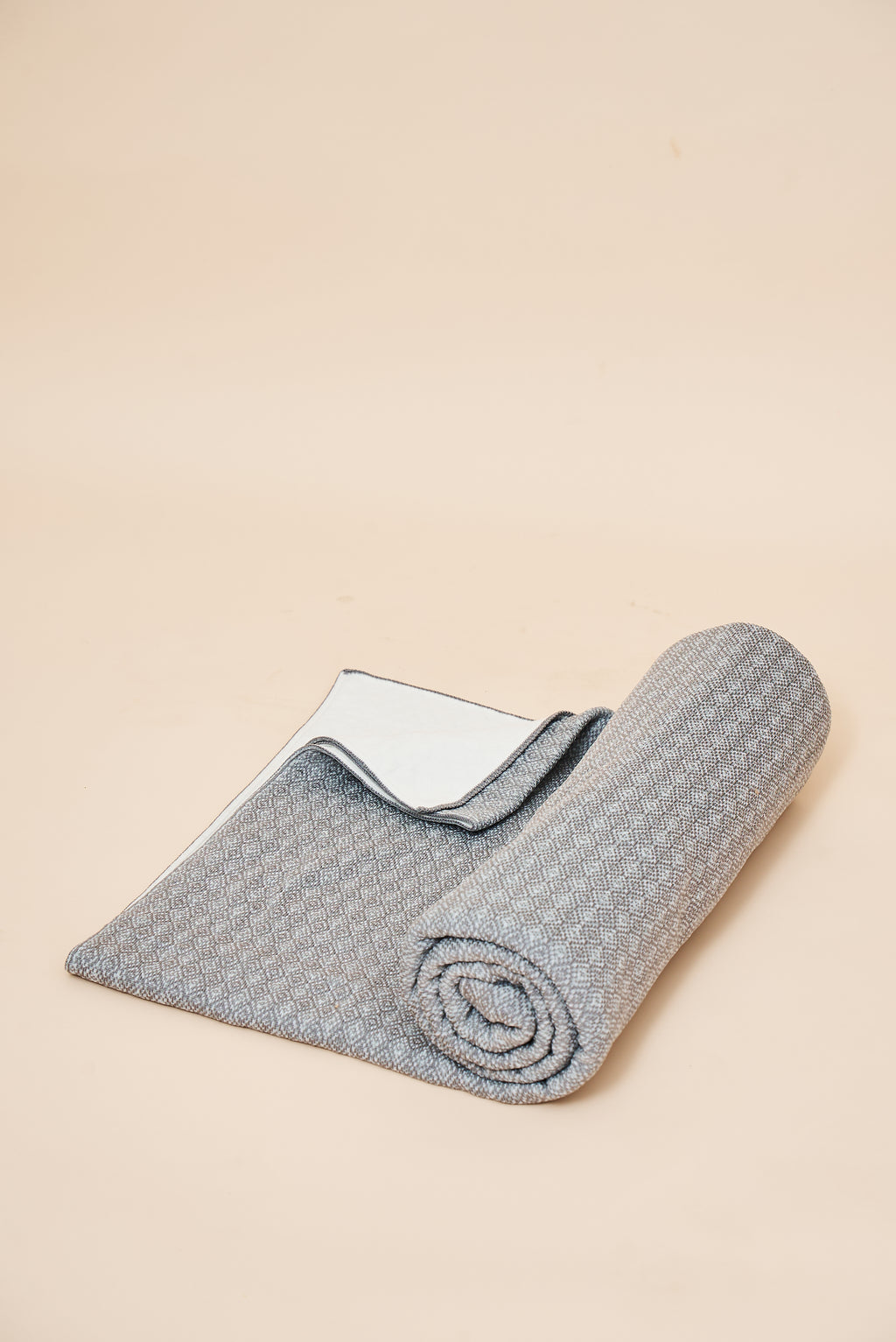Slate self-heating knit throw blanket, rolled, showing the diamond knit and the FibreHeat back