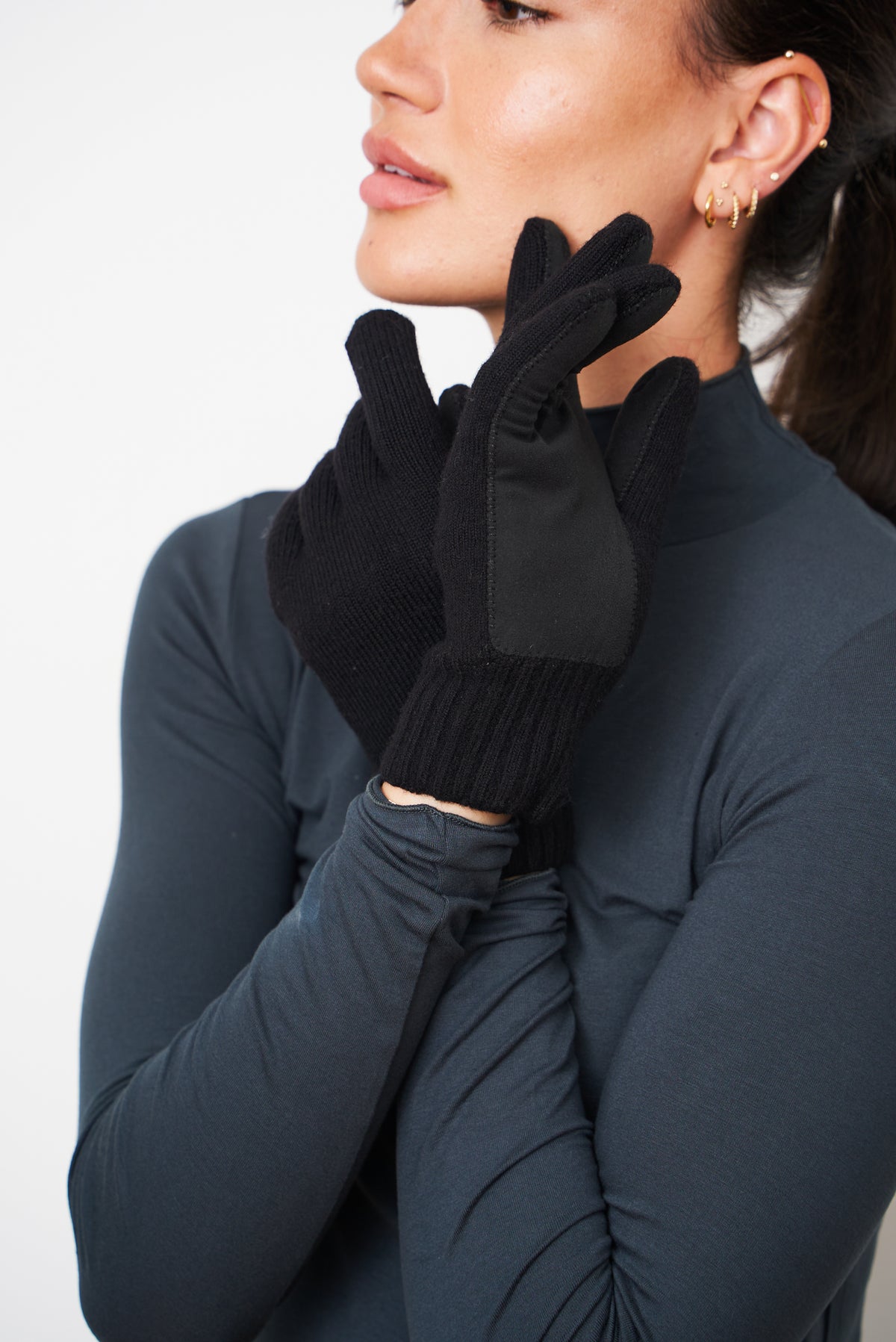 Black merino wool gloves with a self-heating liner, worn close to the face