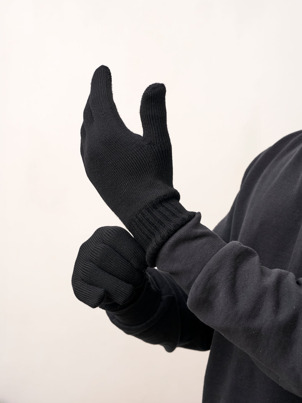 Man pulling on black self-heating merino wool gloves, side view of the ribbed cuff