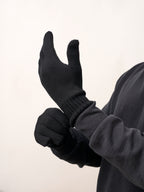 Man pulling on black self-heating merino wool gloves, side view of the ribbed cuff