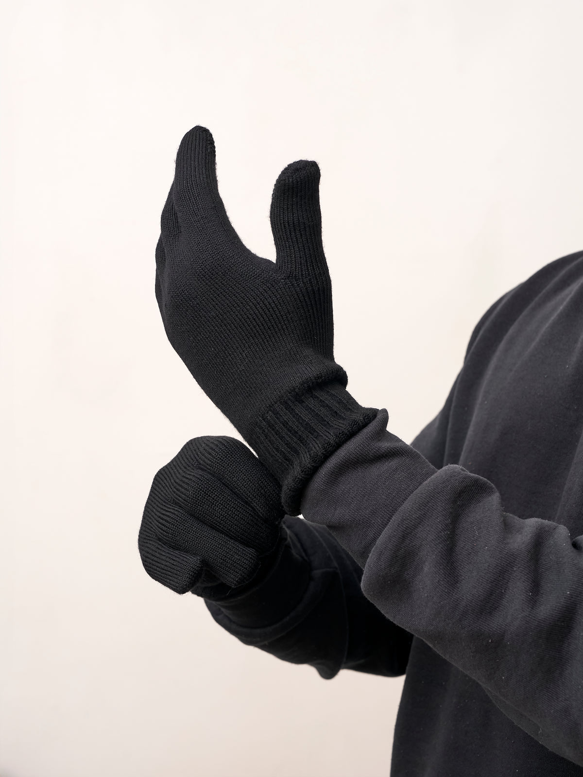 Man pulling on black self-heating merino wool gloves, side view of the ribbed cuff