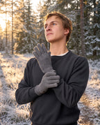 Man wearing slate FibreHeat merino gloves on a frosted forest trail at golden hour
