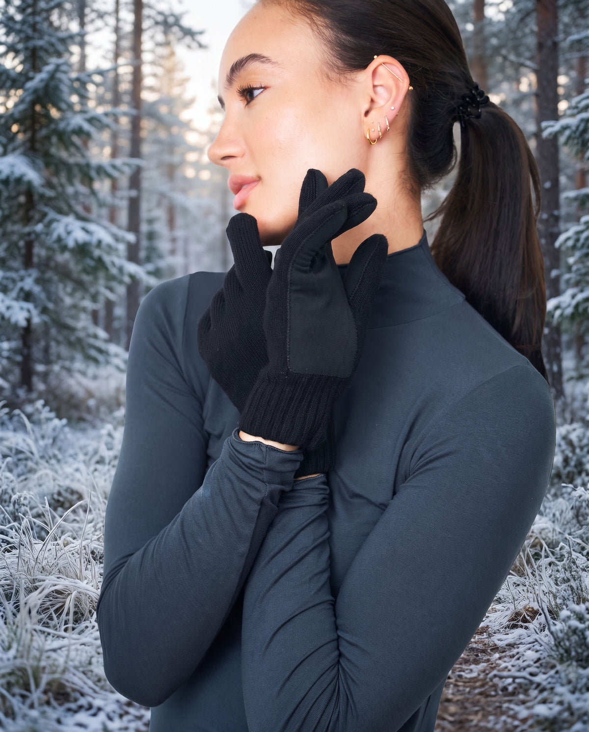 Woman wearing black FibreHeat merino gloves with leather palm patches on a frosted forest trail