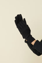 Black self-heating merino wool gloves raised, showing the touchscreen fingertips and ribbed cuffs