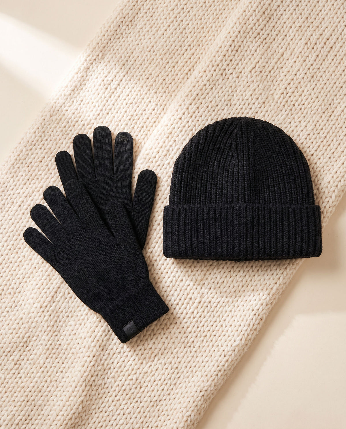 Winter Wonderland bundle: black merino self-heating gloves and black knit beanie on a cream knit throw