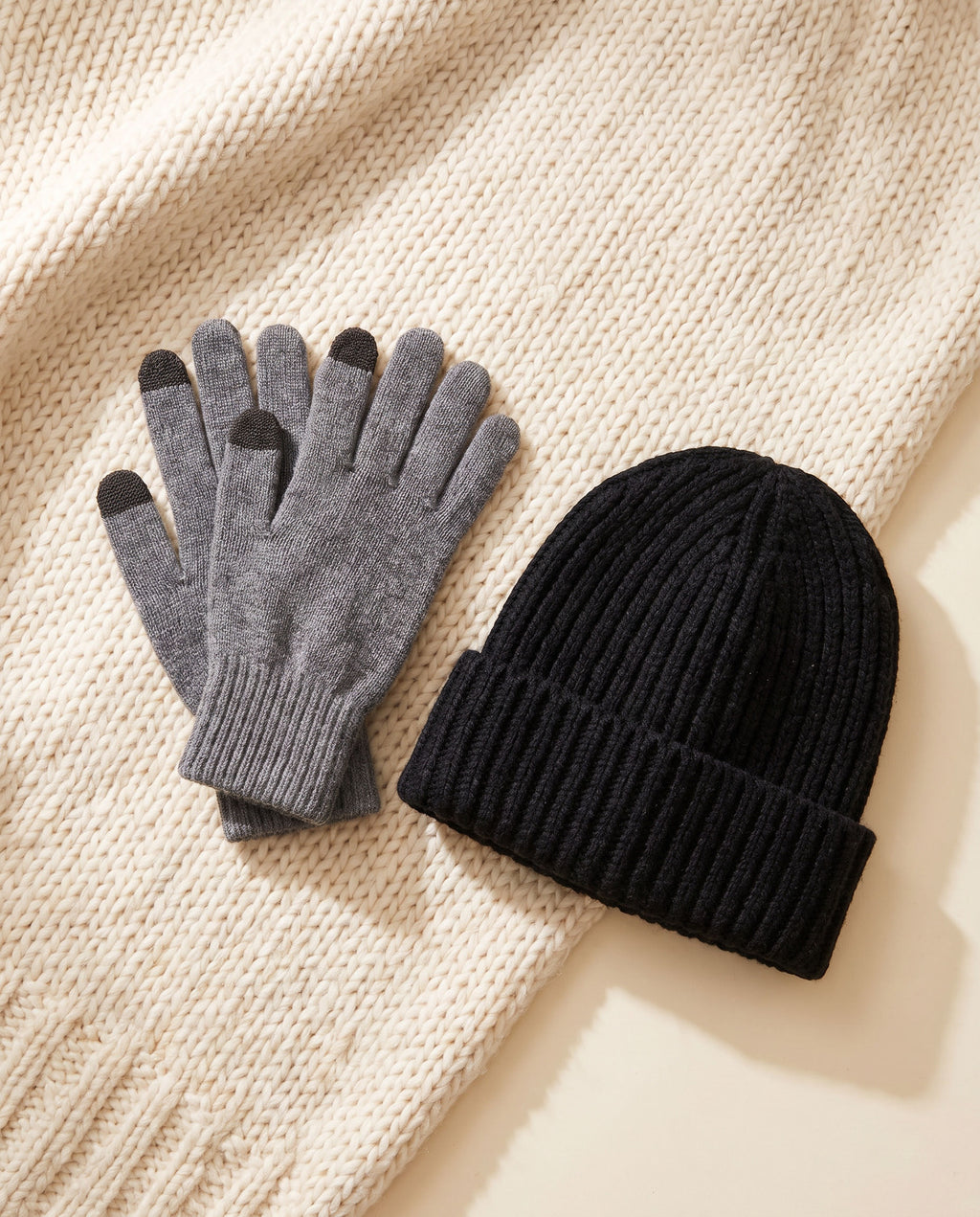 The Warm-Up Bundle: gray heather cashmere gloves and black knit beanie on a cream knit throw