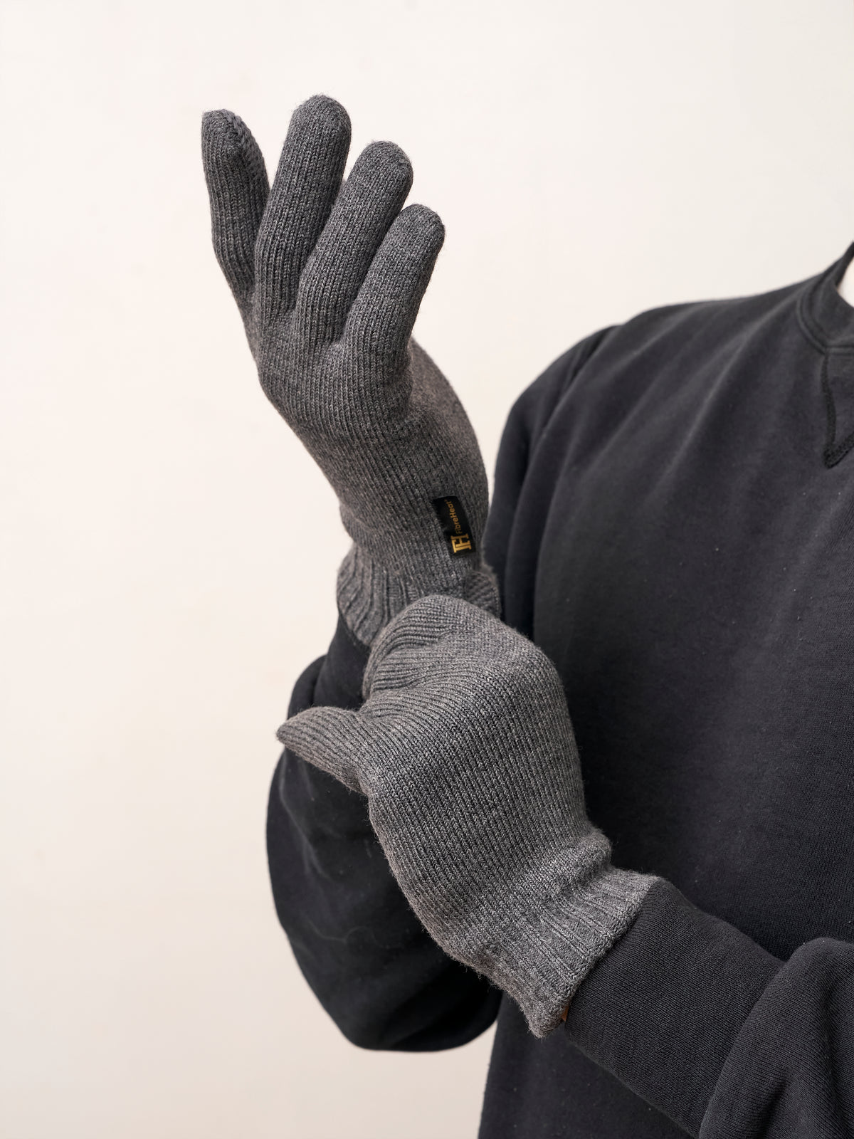 Man pulling on gray self-heating merino wool gloves