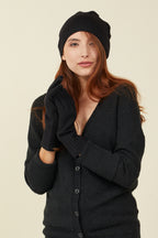 Woman in a black cardigan and beanie wearing black FibreHeat self-heating merino wool gloves